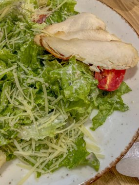Sezar salatası ahşap masa üzerinde tavuk ve parmesan peyniri ile