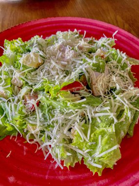 Jambonlu Sezar salatası ve kırmızı tabakta peynir, yakın plan.