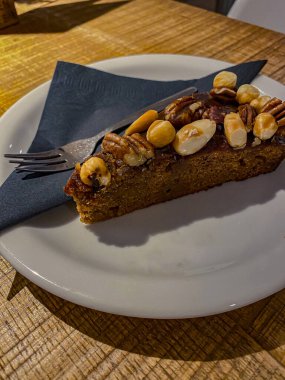 Tahta bir masada beyaz bir tabakta fındıklı çikolatalı pasta.