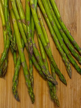 Tahta kesme tahtasının üzerinde taze kuşkonmaz mızrakları.