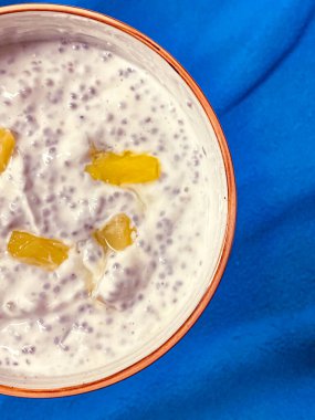 Mavi arka planda bir kasede chia tohumlu Chia tohumu pudingi