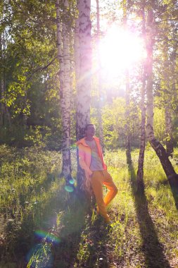 Bir adam gün batımına karşı ormanda duruyor.