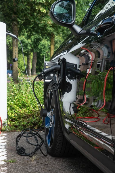 Raalte, Hollanda - 21 Temmuz 2023: Belediye binasının yanındaki bir kamu şarj istasyonunda elektrik SUV şarj ediliyor.