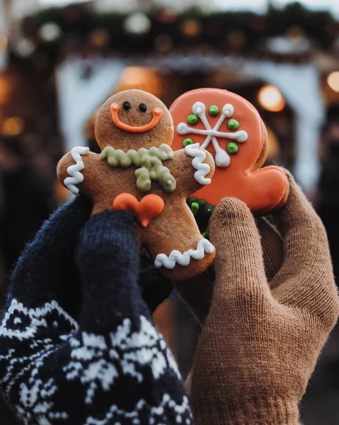 Bir çift ellerinde küçük Noel kurabiyeleri, bir zencefilli kurabiye adamı ve Prag şehrinin arka planında zencefilli kurabiye tutuyor. Çek Cumhuriyeti 'nde Noel ve Yeni Yıl. Eldivenler, eldivenler. 