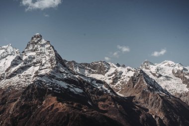 Karla kaplı güzel bir dağ manzarası. Mavi gökyüzü ve kış beyaz ve siyah dağlar. Dağ zirvesi. Dombay