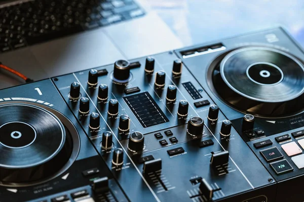 DJ gece kulübünde müzik ve mikserle birlikte masada. DJ partisi, DJ ve müzik konsepti. DJ kontrolörü. Parti, dizüstü bilgisayar, mavi ışık. Müzik stüdyosu, kayıt stüdyosu. Yakın çekim..