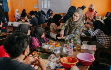 Surabaya, Endonezya, 29 Temmuz 2023 - Okulda aşçılık dersi. Öğretmen kek yapma sürecinde öğrencilere örnekler verir..