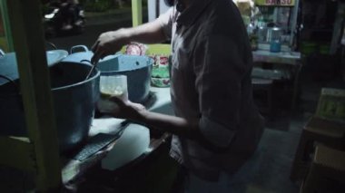 Surabaya, Endonezya, 27 Eylül 2023 - İnsan eli tıraşlı buz küpleri yapar. Geleneksel sokak yemeği satıcısı. Yeşil fasulye lapası..