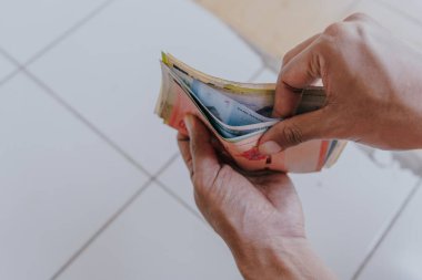 Erkek el ele tutuşur ve çeşitli para birimlerinin banknotlarını sayar. Küresel finans sektörü ekonomik kriz kavramı.