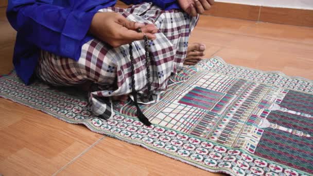 印尼穆斯林男子用手指触摸手中的念珠 双腿交叉坐在祷告席上 礼拜后祈祷 伊斯兰教 Ramadan 崇拜和祈祷概念 4K录像 — 图库视频影像