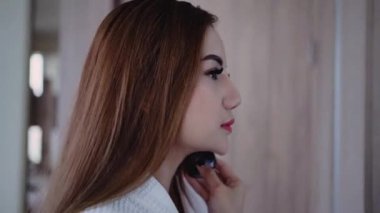 Makyaj aynası ve makyaj malzemeleriyle makyaj aynası önünde duran güzel Asyalı esmer, yatak odasında gülümseyen yüzü olan güzel kız. Sağlık ve zindelik kavramı.