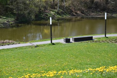 Şehir parkı, deniz kenarında bir patika, bir bank ve bir lamba.