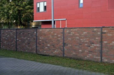 Metal çitli kırmızı tuğla duvar