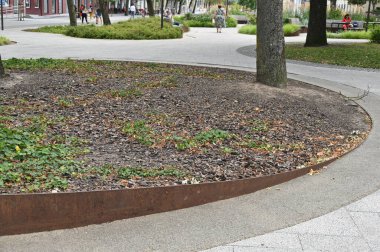 Bir sürü çimen ve küçük bir çiçek tarhı olan küçük bir taşın dikey görüntüsü.