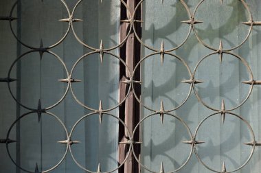 Duvarında beyaz kafes olan metal bir pencere..