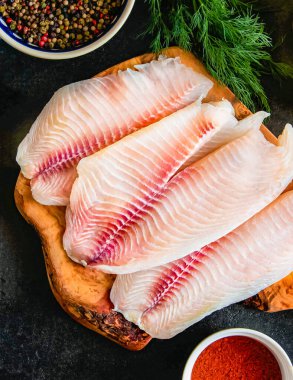 Taze balık fileto pişirme ve baharat doğrama tahtası üzerinde malzemelerle. Organik taze balık