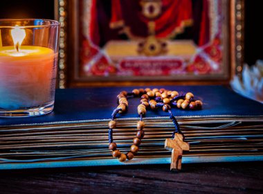 Namaz vakti. Ahşap Tespihler üzerinde eski bir dua kitabı. Tanrı ve İsa'nın anası simgesi. Mum.