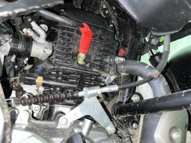 Detaylı yakın plan görüntüler siyah motor bloklu motosiklet motoru, belirgin kırmızı buji botu, çeşitli metal parçaları ve karmaşık kablo bağlantıları..