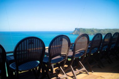 Güneşli bir günde okyanusa bakan sahil restoranındaki koltukta.