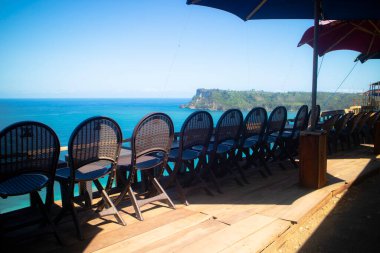 Güneşli bir günde okyanusa bakan sahil restoranındaki koltukta.