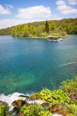 Kozjak Gölü 'ndeki park teknesi yeşil ormanlara karşı, Plitvice Lakes Ulusal Parkı, Hırvatistan