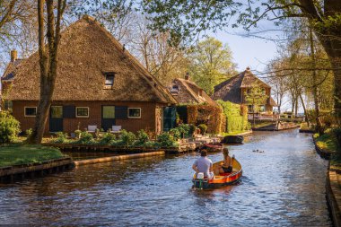 Giethoorn Kanalı 'nda güzel evler ve güzel bitki örtüsüyle tekne gezintisi, Giethoorn, Hollanda