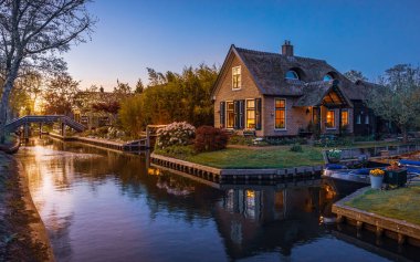 Hollanda, Giethoorn 'daki güzel kanal ve resimli evlerin üzerinde gün batımı.