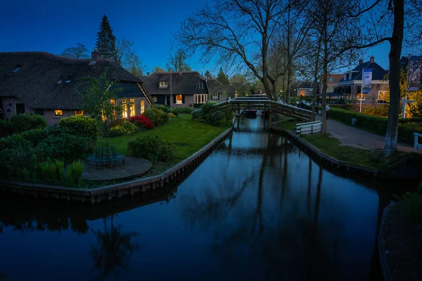 Geceleri kanalı ve aydınlık pencereleri olan güzel manzara, Giethoorn, Hollanda