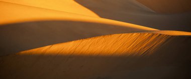 Namib Çölü 'nde gün batımında, Namib-Naukluft Ulusal Parkı' ndaki Walvis Körfezi 'nin güneyinde, kıvrımlı kum tepelerinin kapatılması..