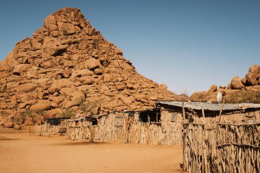 Twyfelfontein, Kunene, Namibya yakınlarındaki Damara kabile köyünde evler. Evler ağaç dalları ve çamurla inşa edilir ve saman eksikliği nedeniyle eğri büğrü metalle kaplıdır..