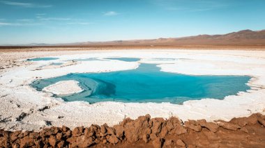 Laguna Escondida de Baltinache 'nin büyüleyici turkuaz suları Atacama Çölü, San Pedro de Atacama, Şili' deki tuz düzlükleriyle ve dağlarla tezat oluşturuyor..