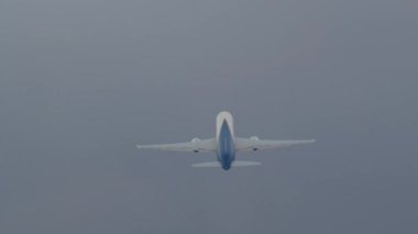 Yolcu uçağı gri bulutlu gökyüzünün arka planına karşı irtifa kazanıyor