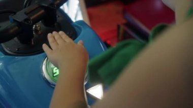 Yukarıdan bakıldığında, bir kız oyun sahasının canlı ışıkları ve sesleri ile çevrili başlama düğmesine basarak bir atari motorsiklet oyununa girişir.