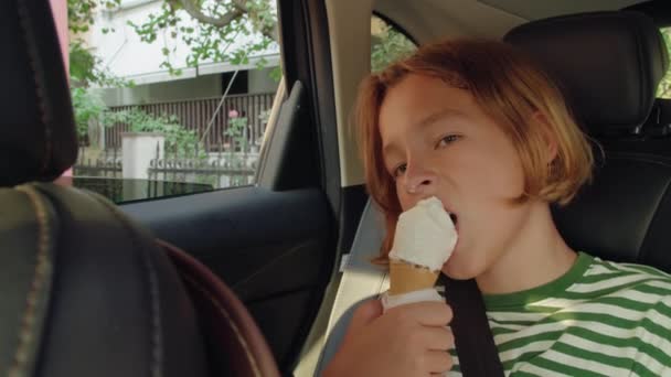 ティーンエイジャー 12歳 ストライプタンクの上に座って 車の後部乗客席に座ってアイスクリームを食べます レジャー デザート — ストック動画