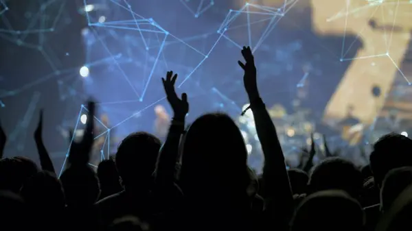 Sahne ışıkları ve canlı müzik bandının olduğu bir konserde siluetli kalabalık arka planda performansını kaybetti.