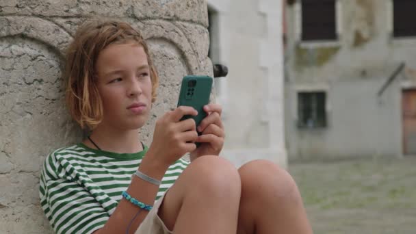 Çizgili Tişörtü Bileziği Olan Bir Çocuk Telefonuna Dikkatle Bakıyor Venedik — Stok video
