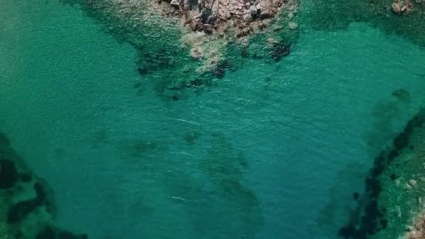 エアリアルショットは 険しい海岸線にブラッシング透明なターコイズウォーターで 隠されたコーブの静かな美しさを明らかにします — ストック動画