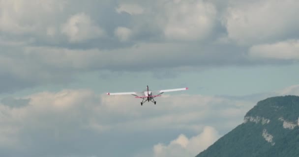 軽い飛行機は険しい山岳地形の上を飛び 背景と目に見える岩のテクスチャで澄んだ空を飛ぶ — ストック動画