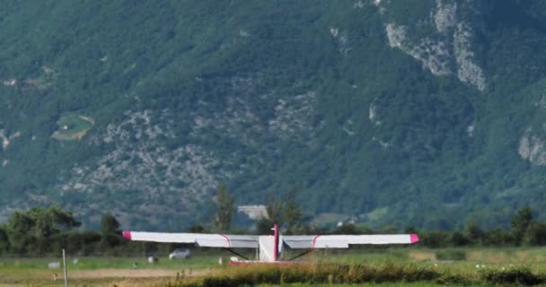 一架以高山为背景的轻型飞机起飞了 底盘也下降了 — 图库视频影像