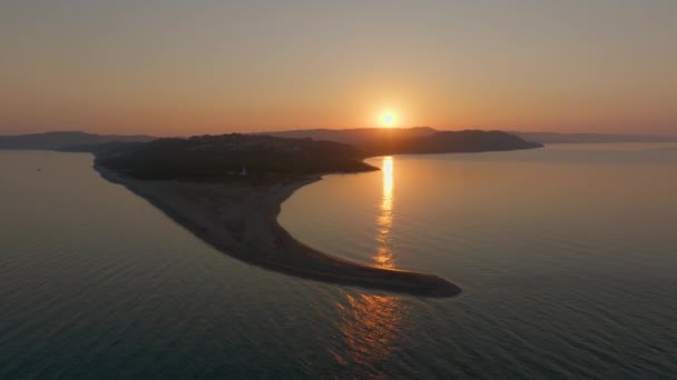 夜明けの最初の光の航空写真は 海のより深いブルースに囲まれたスレンダー沿岸の砂丘の上に太陽が上昇するように 海の上に黄金の道を鋳造します ギリシャ ハラキキ — ストック動画