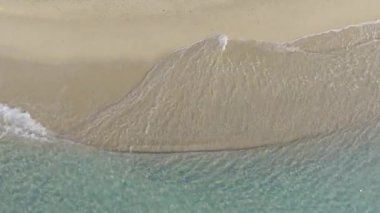 Kumlu bir plajda hafif dalgaların yukarıdan aşağıya doğru görüntüsü