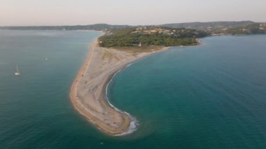 Bir sahil tükürüğünün havadan çekilmiş görüntüsü. Dar sahili turkuaz suları bölüyor. Uçsuz bucaksız sinemalarda bir dron tarafından çekiliyor.