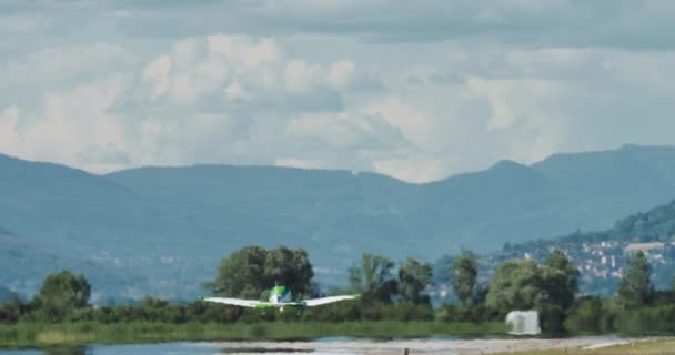 螺旋桨飞机起飞 飞越风景秀丽的山水 背景是一座城镇 — 图库视频影像