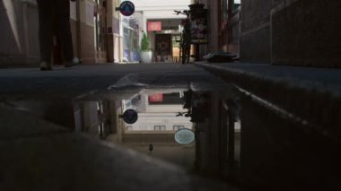 Budapeşte, Macaristan - 27 Haziran 2023: Bir yayanın siluetini ve sokakta bir bisikleti yakalayan bir su birikintisinde yansıma