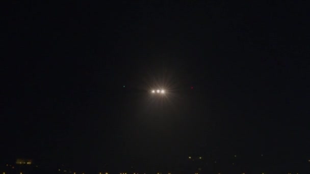 飛行機は夜の着陸のためにライト滑走路に向かって明るいライトで降下します — ストック動画