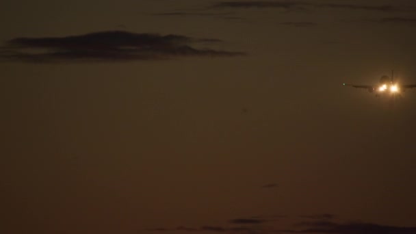 薄い雲が流れる夕日空の背景に明るいヘッドライトで離陸する飛行機 — ストック動画