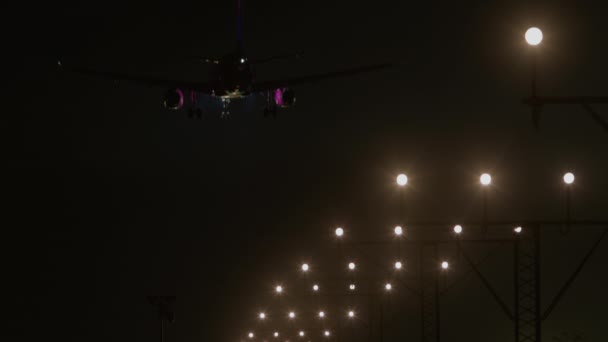 着陸装備と下車ライトが見える航空機のフロントビュー 形成中の明るい滑走路ライトで着陸する準備 — ストック動画