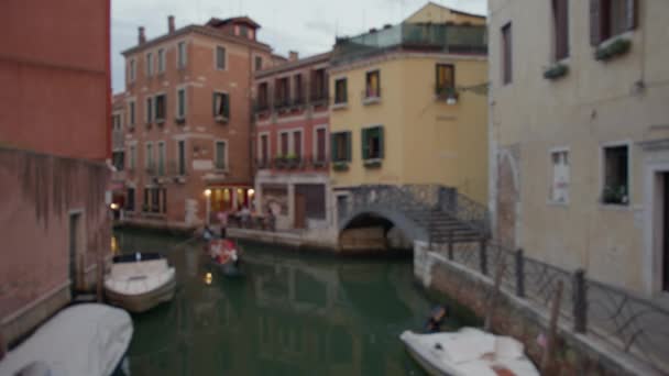Gondola Moves Venice Canal Dusk Moored Boats Pedestrian Bridge Backdrop — Stock Video