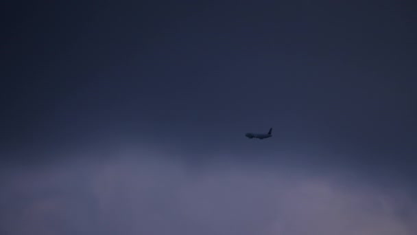 高高度の飛行機は 空に集まる夕暮れの背景に対して 雲の後ろに隠れて飛び去ります — ストック動画
