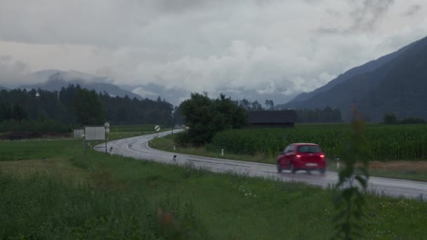 Röd Bil Kör Längs Våt Landsväg Slingrande Genom Gröna Fält — Stockvideo